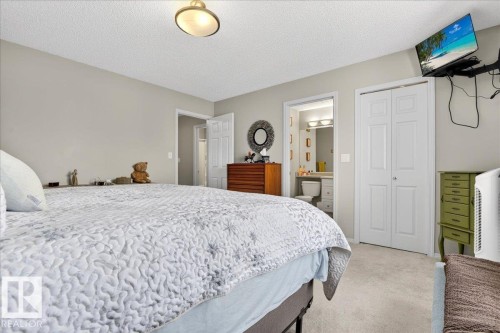 Bedroom with carpet flooring, a textured ceiling, a closet, and ensuite bathroom - 23 4020 21 Street, Edmonton, AB - Indoor Photo Showing Bedroom