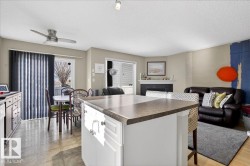 Kitchen with dark countertops, open floor plan, a breakfast bar area, white cabinetry, and a textured ceiling - 