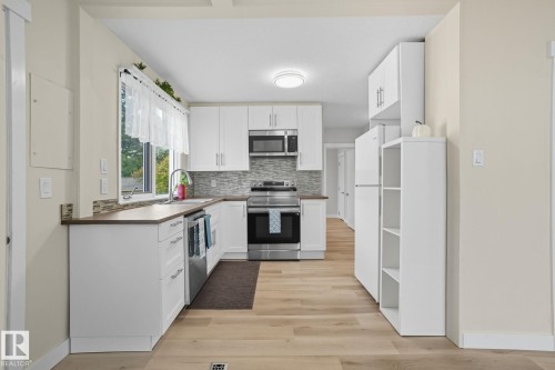 Kitchen featuring white cabinetry, tasteful backsplash, appliances with stainless steel finishes, light wood-style floors, and open shelves - 11222 71 Avenue, Edmonton, AB - Indoor Photo Showing Kitchen With Stainless Steel Kitchen With Upgraded Kitchen
