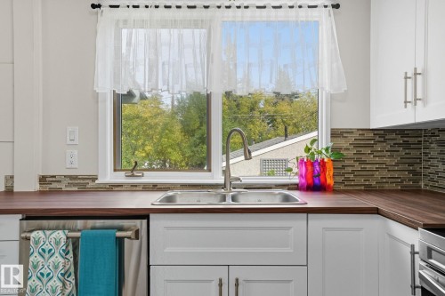 Kitchen with white cabinetry, appliances with stainless steel finishes, butcher block countertops, and tasteful backsplash - 11222 71 Avenue, Edmonton, AB - Indoor Photo Showing Kitchen With Double Sink