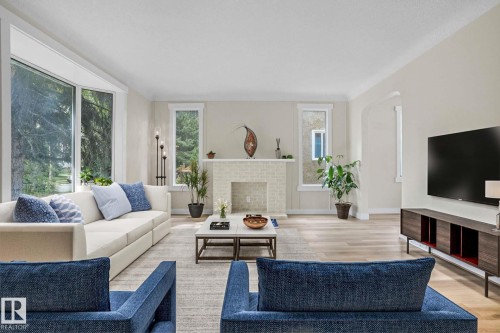 Living area with wood finished floors, arched walkways, and a decorative fireplace - 11222 71 Avenue, Edmonton, AB - Indoor Photo Showing Living Room With Fireplace