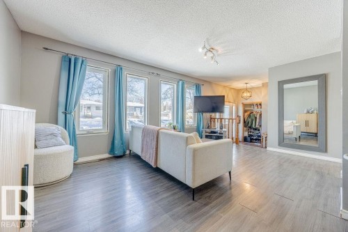 Living room featuring healthy amount of natural light, a textured ceiling, wood finished floors, and track lighting - 12253 95A Street, Edmonton, AB - Indoor Photo Showing Living Room