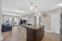 Kitchen featuring a kitchen breakfast bar, open floor plan, pendant lighting, light wood-style flooring, and dark wood finish cabinetry - 