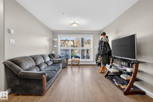 Living room featuring baseboards and light wood-type flooring - 104 8515 99 Street, Edmonton, AB - Indoor Photo Showing Living Room