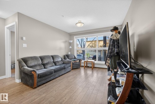 Living room with light wood-style floors and a baseboard radiator - 104 8515 99 Street, Edmonton, AB - Indoor Photo Showing Living Room