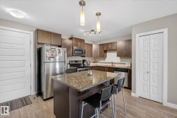 Kitchen featuring a breakfast bar, stainless steel appliances, dark wood finish cabinets, pendant lighting, and dark stone counters - 