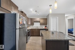 Kitchen with stainless steel appliances, pendant lighting, light wood finished floors, a kitchen island, and dark wood finish cabinets - 