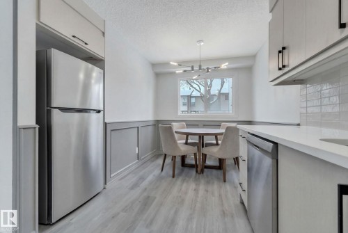 Kitchen with stainless steel appliances, light countertops, suspended lighting, wainscoting, and a decorative wall - 1281 Hooke Road, Edmonton, AB - Indoor Photo Showing Other Room