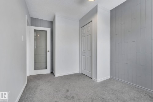 Unfurnished bedroom featuring carpet flooring, a closet, a textured ceiling, and wooden walls - 1281 Hooke Road, Edmonton, AB - Indoor Photo Showing Other Room