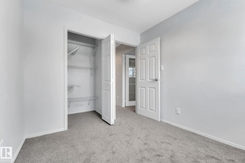 Unfurnished bedroom featuring light carpet, a textured ceiling, and a spacious closet - 1281 Hooke Road, Edmonton, AB - Indoor Photo Showing Other Room