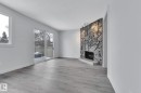 Unfurnished living room featuring a stone fireplace, a textured ceiling, and light wood finished floors - 1281 Hooke Road, Edmonton, AB  - Indoor Photo Showing Living Room With Fireplace 