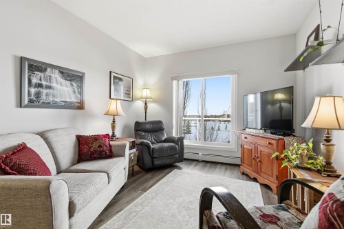 Living area featuring a baseboard heating unit and wood finished floors - 313 263 Macewan Road, Edmonton, AB - Indoor Photo Showing Living Room