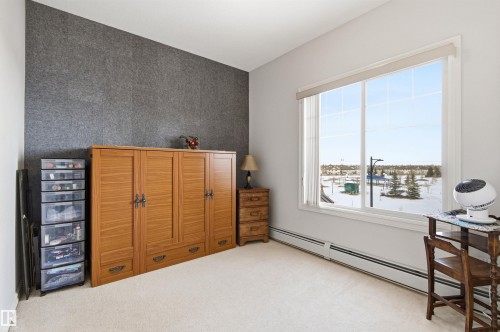 Carpeted bedroom featuring an accent wall and a baseboard radiator - 313 263 Macewan Road, Edmonton, AB - Indoor