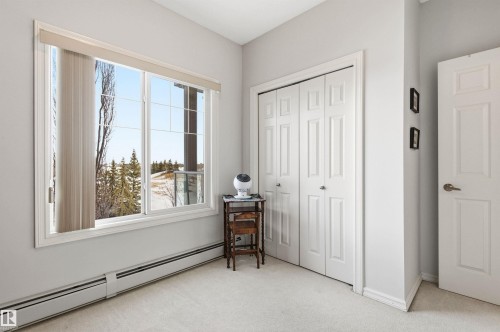 Bedroom with a baseboard radiator, light carpet, and a closet - 313 263 Macewan Road, Edmonton, AB - Indoor