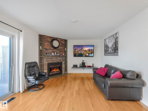 Living room with light wood-style floors and a large fireplace - 61 9520 174 Street, Edmonton, AB - Indoor Photo Showing Living Room With Fireplace
