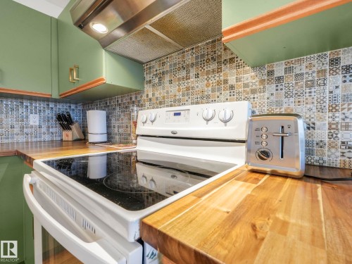 Kitchen with electric range, wooden counters, green cabinets, and decorative backsplash - 61 9520 174 Street, Edmonton, AB - Indoor Photo Showing Kitchen