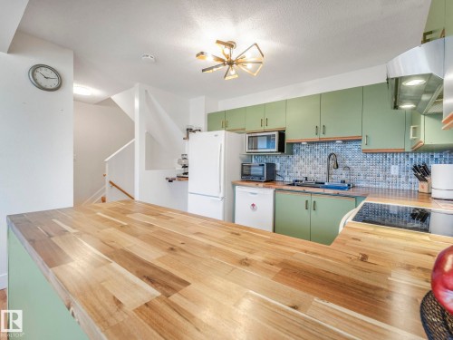 Kitchen featuring green cabinetry, tasteful backsplash, white appliances, and exhaust hood - 61 9520 174 Street, Edmonton, AB - Indoor Photo Showing Kitchen