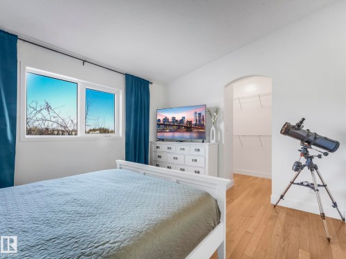 Bedroom featuring arched walkways, hardwood / wood-style flooring, a walk in closet, and lofted ceiling - 61 9520 174 Street, Edmonton, AB - Indoor Photo Showing Bedroom