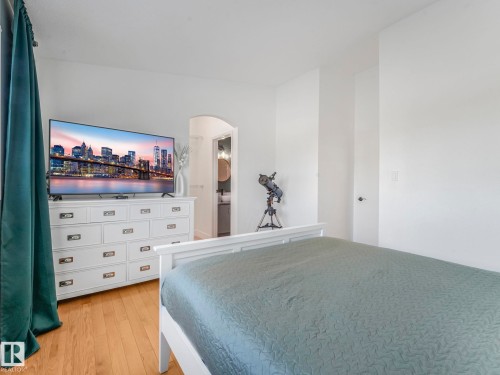 Bedroom with light wood-style flooring, arched walkways, and connected bathroom - 61 9520 174 Street, Edmonton, AB - Indoor Photo Showing Bedroom