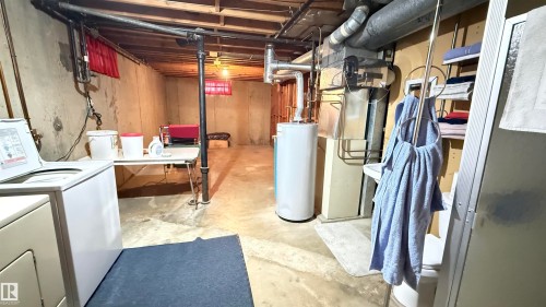 Unfinished basement with water heater, heating unit, and independent washer and dryer - 4608 102 Avenue, Edmonton, AB - Indoor Photo Showing Basement