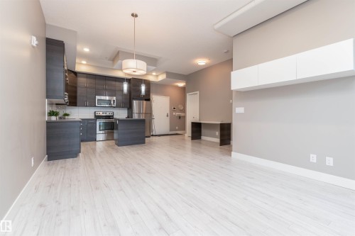 Kitchen featuring modern cabinets, stainless steel appliances, a center island, backsplash, and open floor plan - 105 10006 83 Avenue, Edmonton, AB - Indoor Photo Showing Kitchen