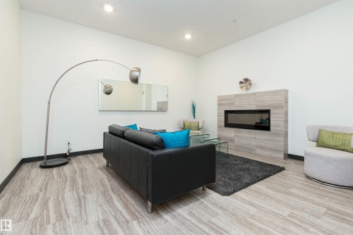 Lobby room featuring a tile fireplace, light wood finished floors, and recessed lighting - 105 10006 83 Avenue, Edmonton, AB - Indoor Photo Showing Other Room With Fireplace