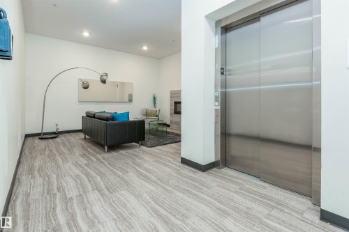 Lobby room featuring elevator, light wood-style flooring, a glass covered fireplace, and recessed lighting - 105 10006 83 Avenue, Edmonton, AB - Indoor