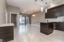 Kitchen featuring dark wood finish cabinetry, open floor plan, pendant lighting, a kitchen island, and light wood-type flooring - 105 10006 83 Avenue, Edmonton, AB  - Indoor Photo Showing Kitchen 