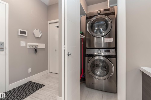 Laundry area with stacked washing machine and dryer and light wood-type flooring - 105 10006 83 Avenue, Edmonton, AB - Indoor Photo Showing Laundry Room