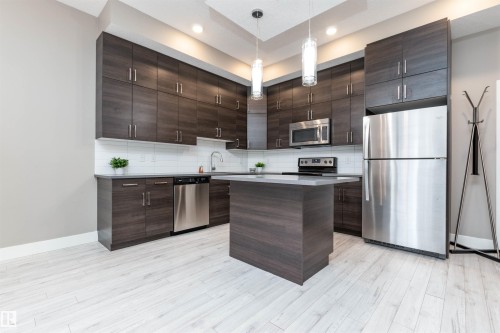 Kitchen featuring dark wood finish cabinets, stainless steel appliances, and a center island - 105 10006 83 Avenue, Edmonton, AB - Indoor Photo Showing Kitchen With Stainless Steel Kitchen