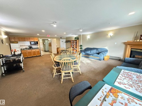 Dining area with crown molding, dark carpet, recessed lighting, a fireplace, and a baseboard heating unit - 302 8215 84 Avenue, Edmonton, AB - Indoor With Fireplace