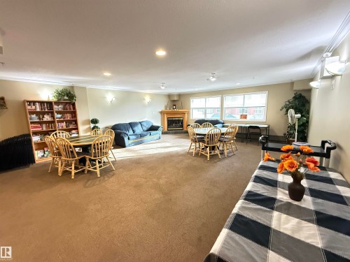 Carpeted living room with ornamental molding, a glass covered fireplace, and recessed lighting - 302 8215 84 Avenue, Edmonton, AB - Indoor