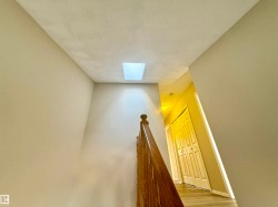Stairs featuring a skylight, a textured ceiling, and wood finished floors - 