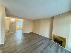 Unfurnished living room with a textured ceiling, wood finished floors, and a glass covered fireplace - 