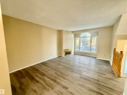 Unfurnished living room featuring wood finished floors, a textured ceiling, a glass covered fireplace, and heating unit - 