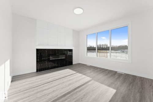 Unfurnished living room with light wood-style flooring and a glass covered fireplace - 3 Pierwyck Loop, Spruce Grove, AB - Indoor Photo Showing Living Room With Fireplace