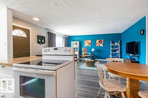 Kitchen featuring electric range, wooden counters, dark wood-type flooring, white cabinetry, and a textured ceiling - 4628 46 Ave, Evansburg, AB - Indoor Photo Showing Laundry Room
