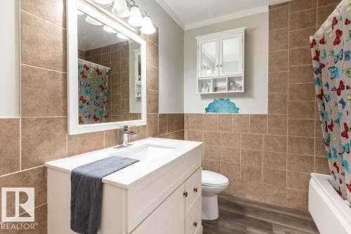 Bathroom with vanity, tile walls, dark wood-style floors, crown molding, and shower / bath combination with curtain - 4628 46 Ave, Evansburg, AB - Indoor Photo Showing Bathroom