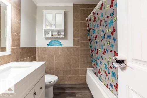 Bathroom with vanity, tile walls, dark wood finished floors, shower / bath combo, and ornamental molding - 4628 46 Ave, Evansburg, AB - Indoor Photo Showing Bathroom