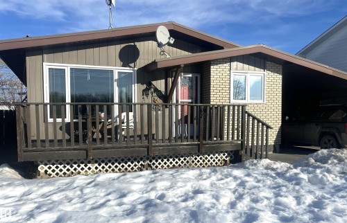 Back of property with brick siding, a wooden deck, and an attached carport - 4628 46 Ave, Evansburg, AB - Outdoor With Deck Patio Veranda