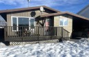 Back of property with brick siding, a wooden deck, and an attached carport - 4628 46 Ave, Evansburg, AB  - Outdoor With Deck Patio Veranda 