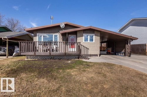 View of front of home with a deck, a carport, a front yard, and brick siding - 4628 46 Ave, Evansburg, AB - Outdoor With Deck Patio Veranda