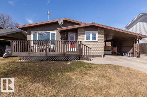View of front of home featuring a wooden deck, an attached carport, brick siding, a front lawn, and driveway - 4628 46 Ave, Evansburg, AB - Outdoor With Deck Patio Veranda