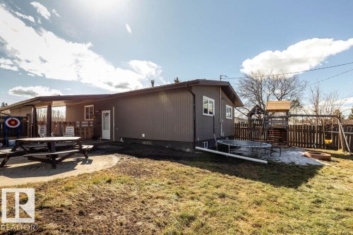 Rear view of property featuring a trampoline, a patio area, a playground, and a fire pit - 4628 46 Ave, Evansburg, AB - Outdoor With Deck Patio Veranda