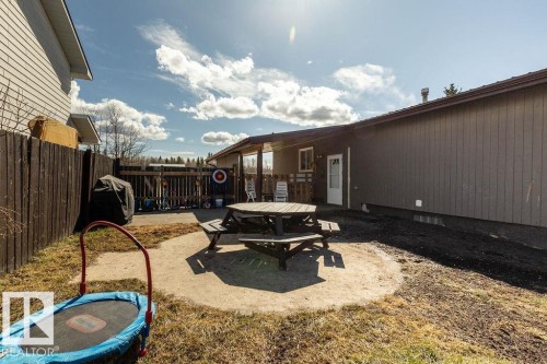 Fenced backyard featuring a patio area, outdoor dining space, and a trampoline - 4628 46 Ave, Evansburg, AB - Outdoor With Deck Patio Veranda