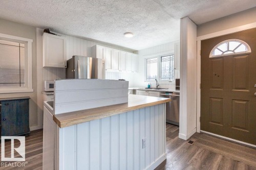 Kitchen with white cabinets, stainless steel appliances, butcher block countertops, a kitchen island, and dark wood-style flooring - 4628 46 Ave, Evansburg, AB - Indoor Photo Showing Kitchen