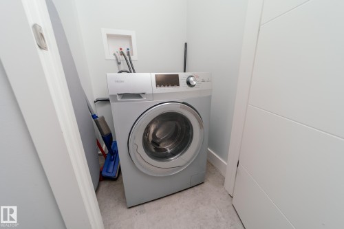 Laundry area featuring washer / clothes dryer and concrete floors - 70 446 Allard Boulevard, Edmonton, AB - Indoor Photo Showing Laundry Room