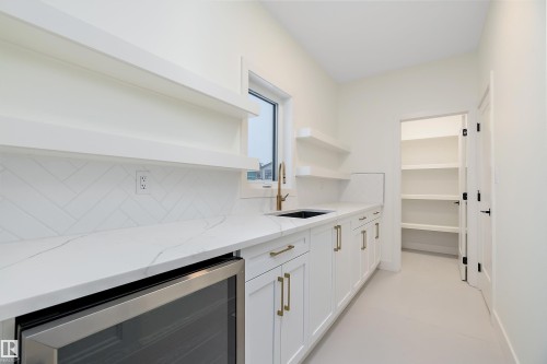 Bar area with open shelves, beverage cooler, white cabinets, light stone countertops, and backsplash - Edmonton, AB - Indoor Photo Showing Kitchen
