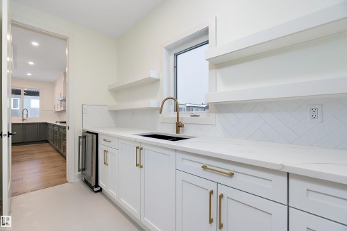 Dual tone kitchen with open shelves, light stone counters, dual tone cabinetry, backsplash, and wine cooler - Edmonton, AB - Indoor Photo Showing Kitchen With Double Sink
