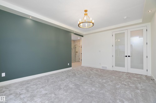Carpeted spare room with french doors, suspended lighting, and a raised ceiling - Edmonton, AB - Indoor Photo Showing Other Room